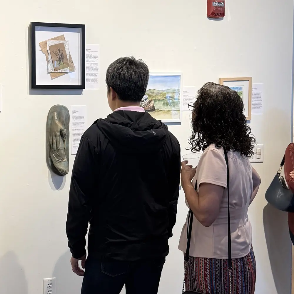 Two visitors at the Memory Lane opening, seen from behind, facing a gallery wall with Fracture hanging at upper left