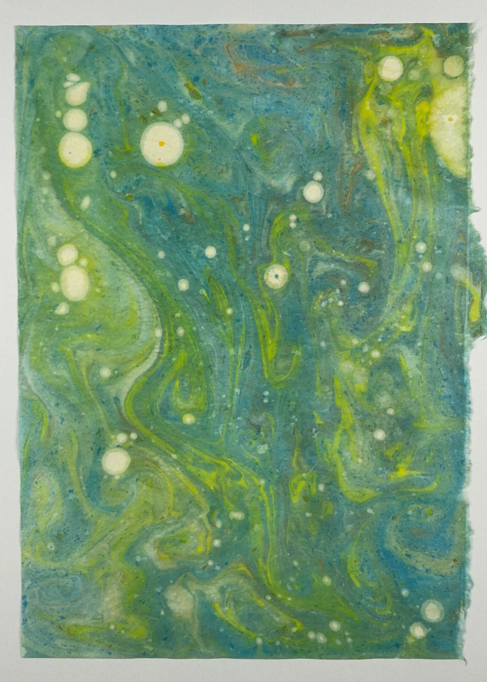 Paper marbling monoprint with layered color and stone-thrown patterns