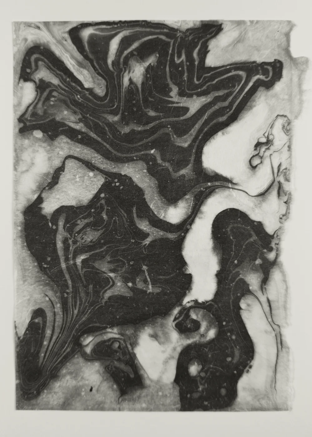 Black and white suminagashi monotype with concentric ink rings on washi paper