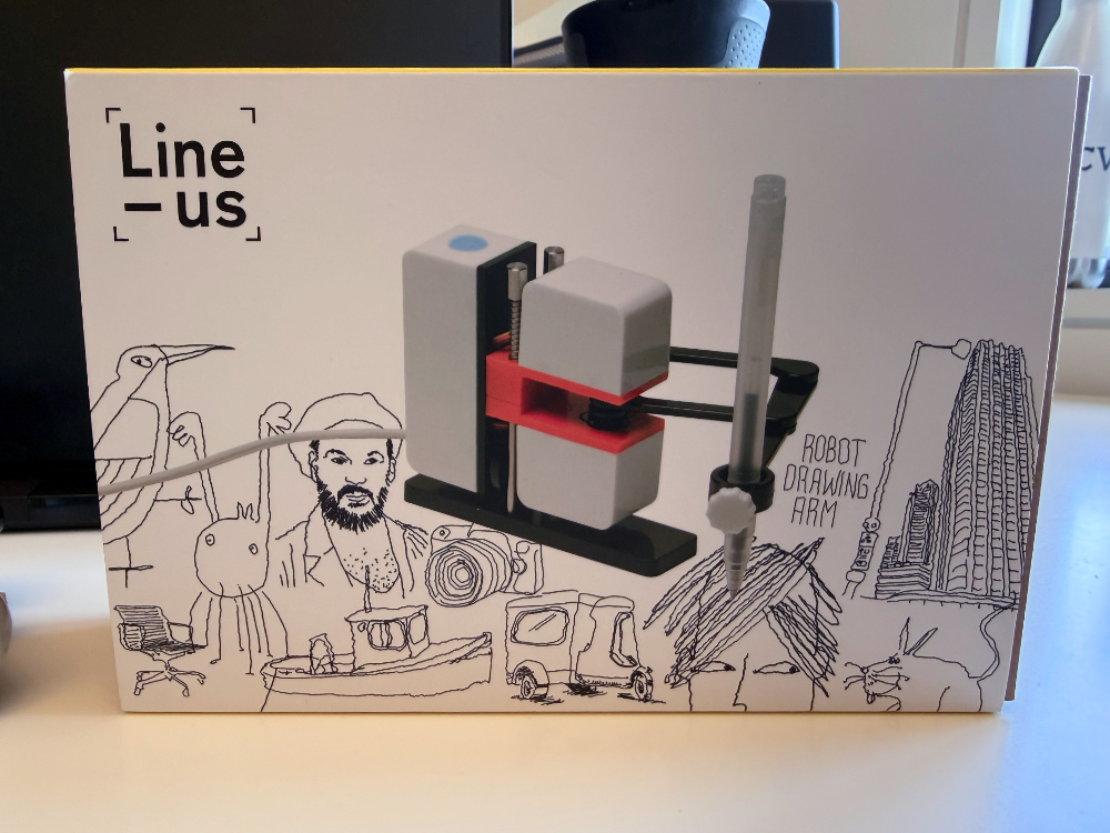 Line-us drawing robot in its retail packaging, surrounded by the brand's signature wobbly line illustrations